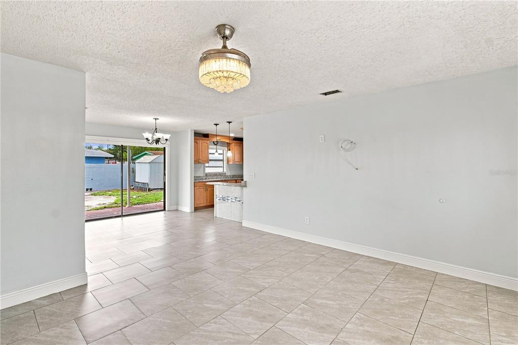 An open-concept living area with tiled floors, a crystal ceiling fan, and an adjacent kitchen — 4606 BYERLE CIRCLE, TAMPA, FL