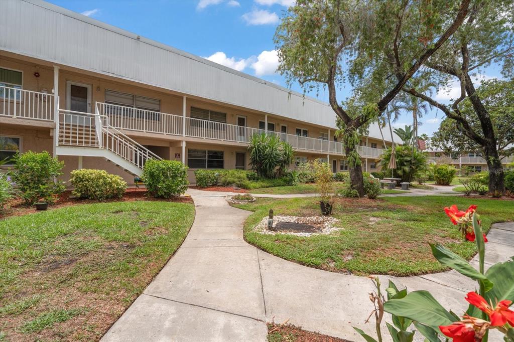 A two-story apartment building with a white balcony railing and a concrete walkway outside — 10033 64TH AVENUE N UNIT 19, ST PETERSBURG, FL