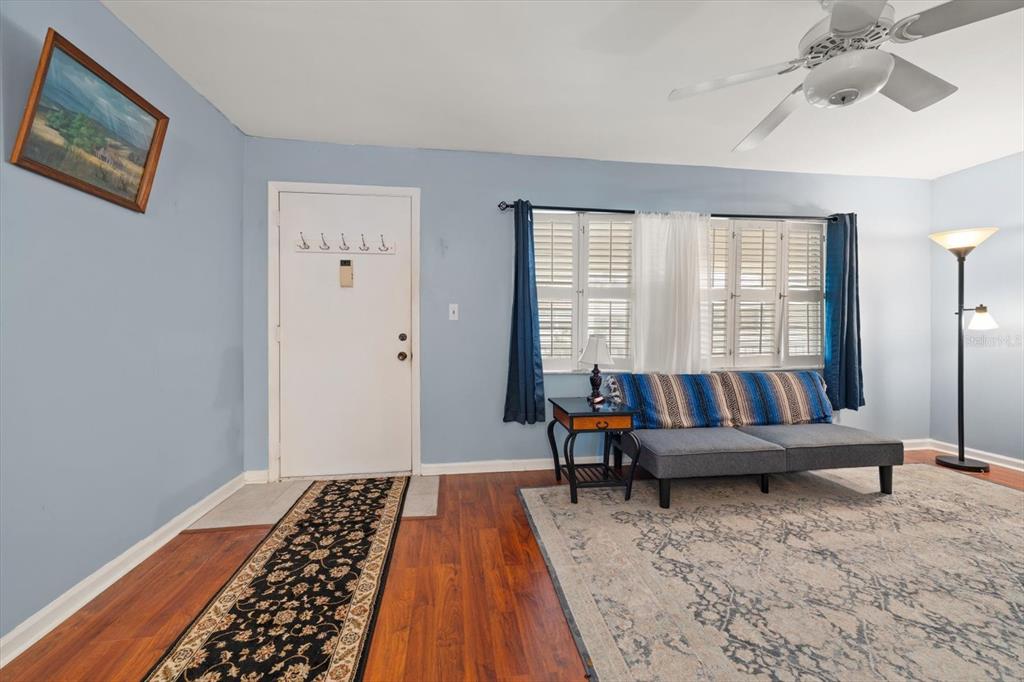 A living room with light blue walls, wood flooring, a sofa, and a ceiling fan — 10033 64TH AVENUE N UNIT 19, ST PETERSBURG, FL