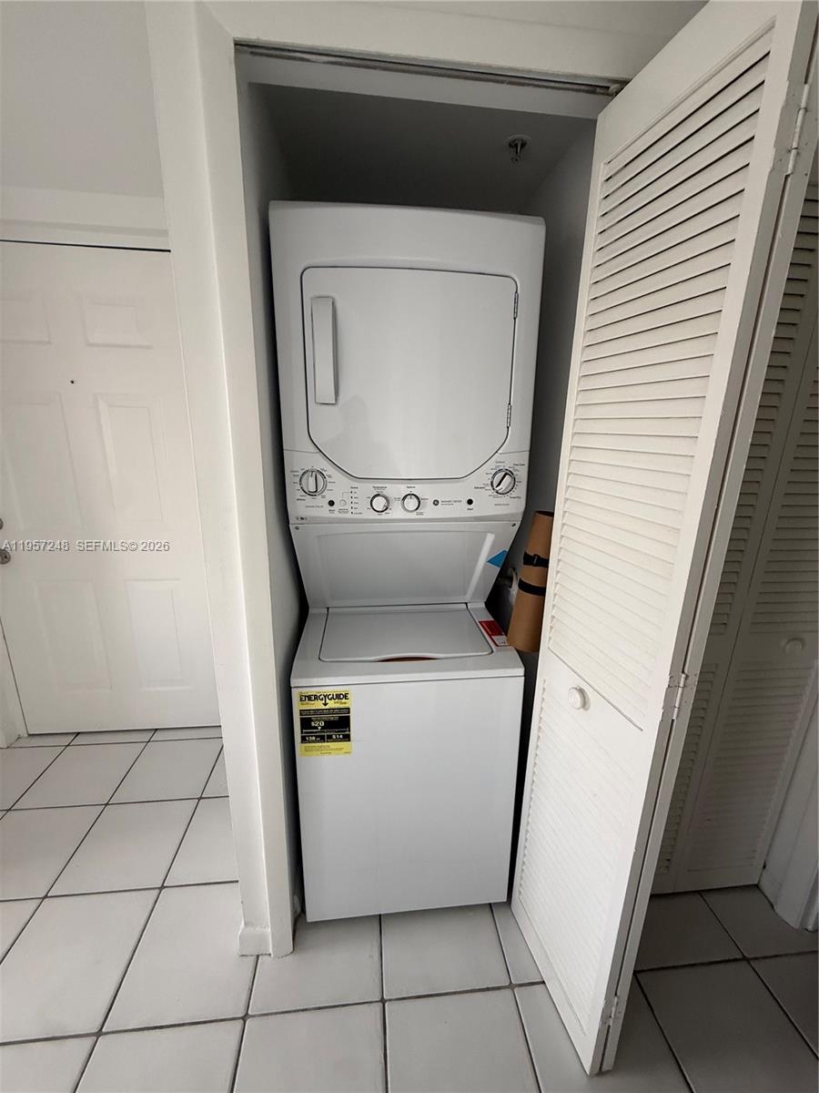 A white stacked washer and dryer unit sits inside a small closet with louvered doors — 3052 SW 27th Ave # 301, Miami FL 33133, MIAMI, FL