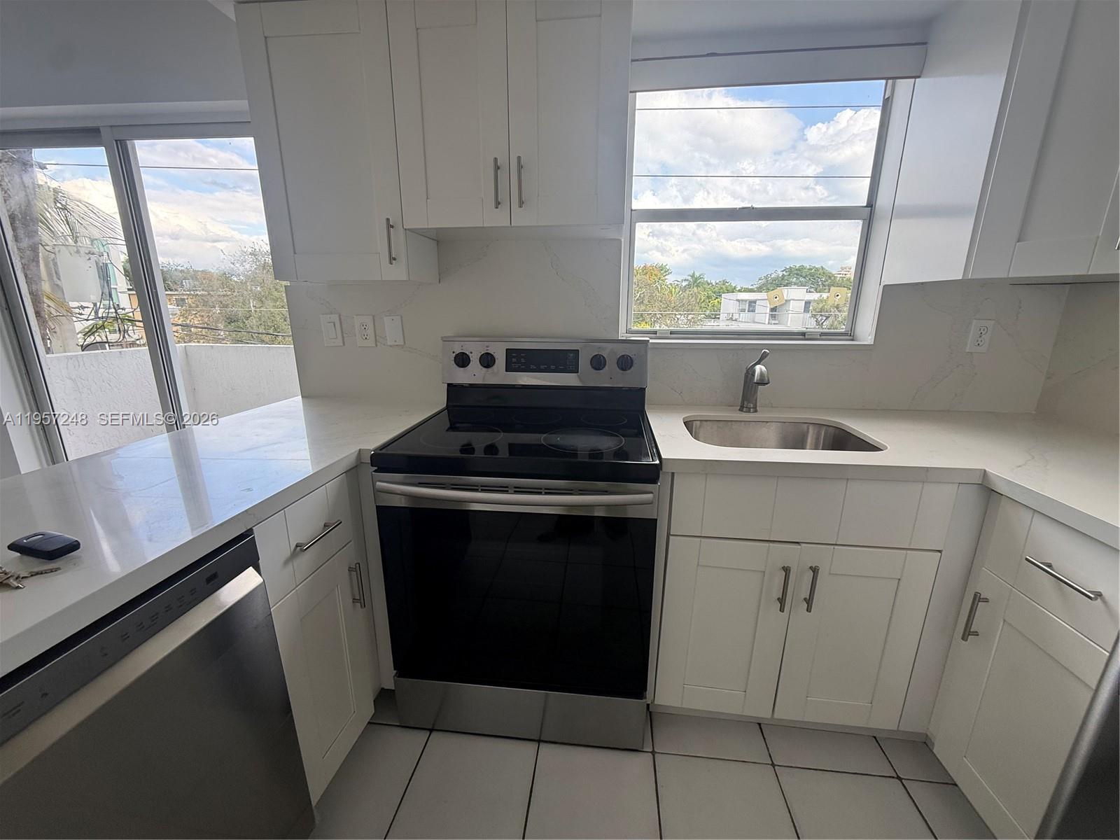 A kitchen features white cabinets, stainless steel appliances, a sink, and a window view — 3052 SW 27th Ave # 301, Miami FL 33133, MIAMI, FL