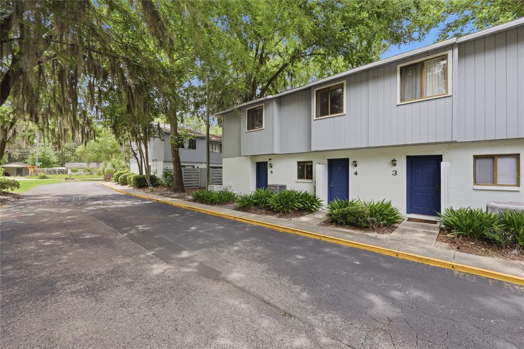 A two-story apartment building with blue doors and gray siding sits beside a paved road — 3600 SW 19TH AVENUE UNIT 5D, GAINESVILLE, FL