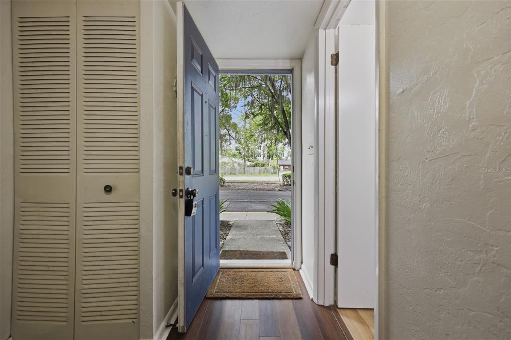 An open blue front door reveals a view of a sidewalk and trees outside — 3600 SW 19TH AVENUE UNIT 5D, GAINESVILLE, FL
