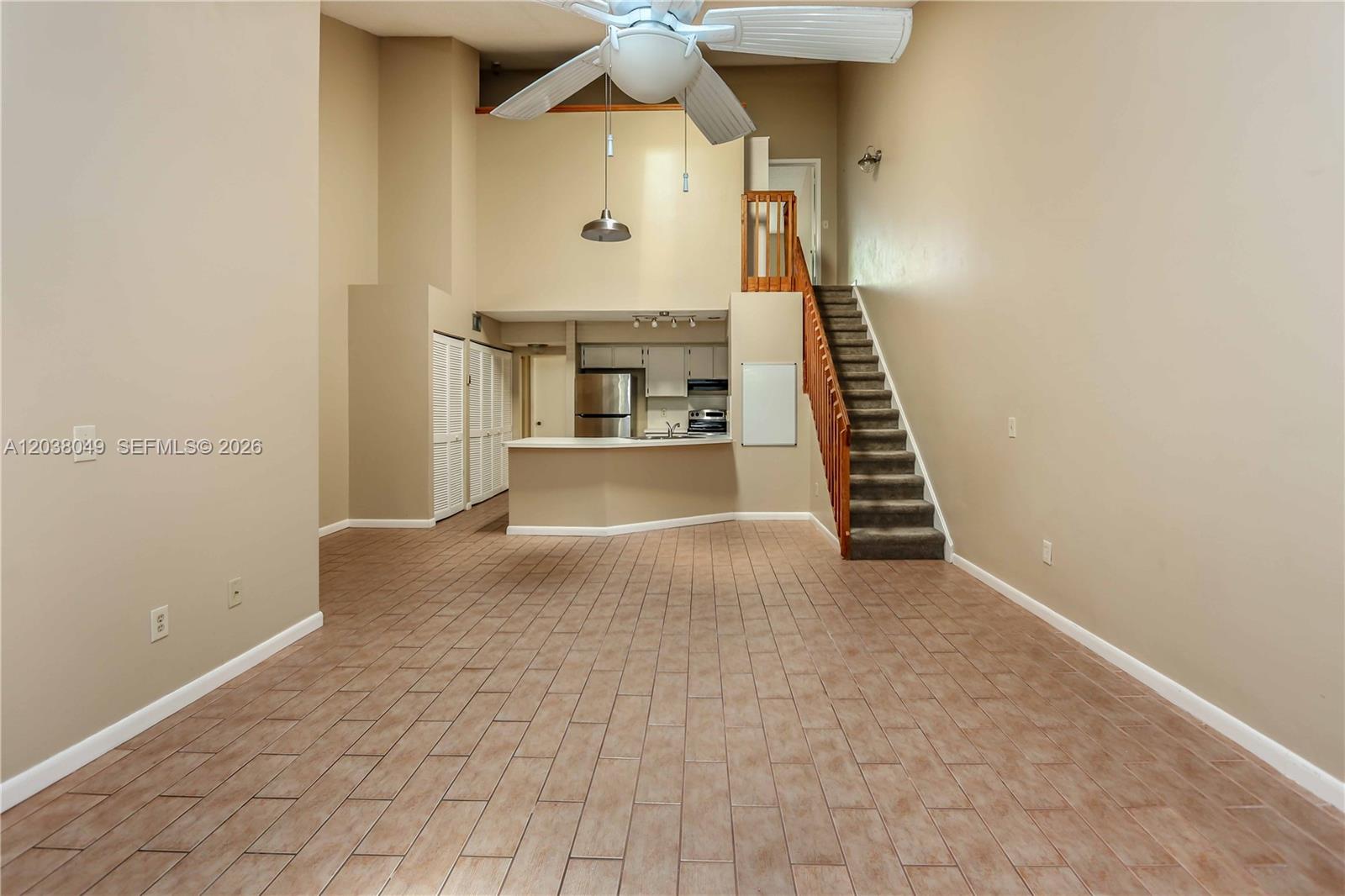 A living area with tile floors, a kitchen counter, and stairs leading to a loft — 444 SE 14th St, Dania Beach FL 33004, DANIA BEACH, FL
