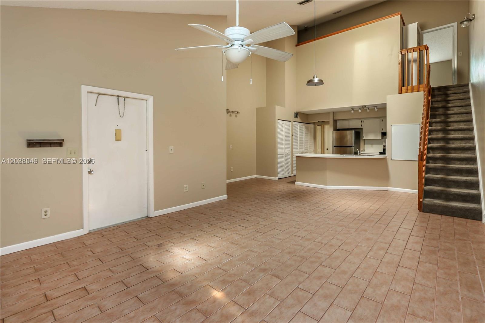 A living area with tile flooring, a ceiling fan, and stairs leading to an upper level — 444 SE 14th St, Dania Beach FL 33004, DANIA BEACH, FL