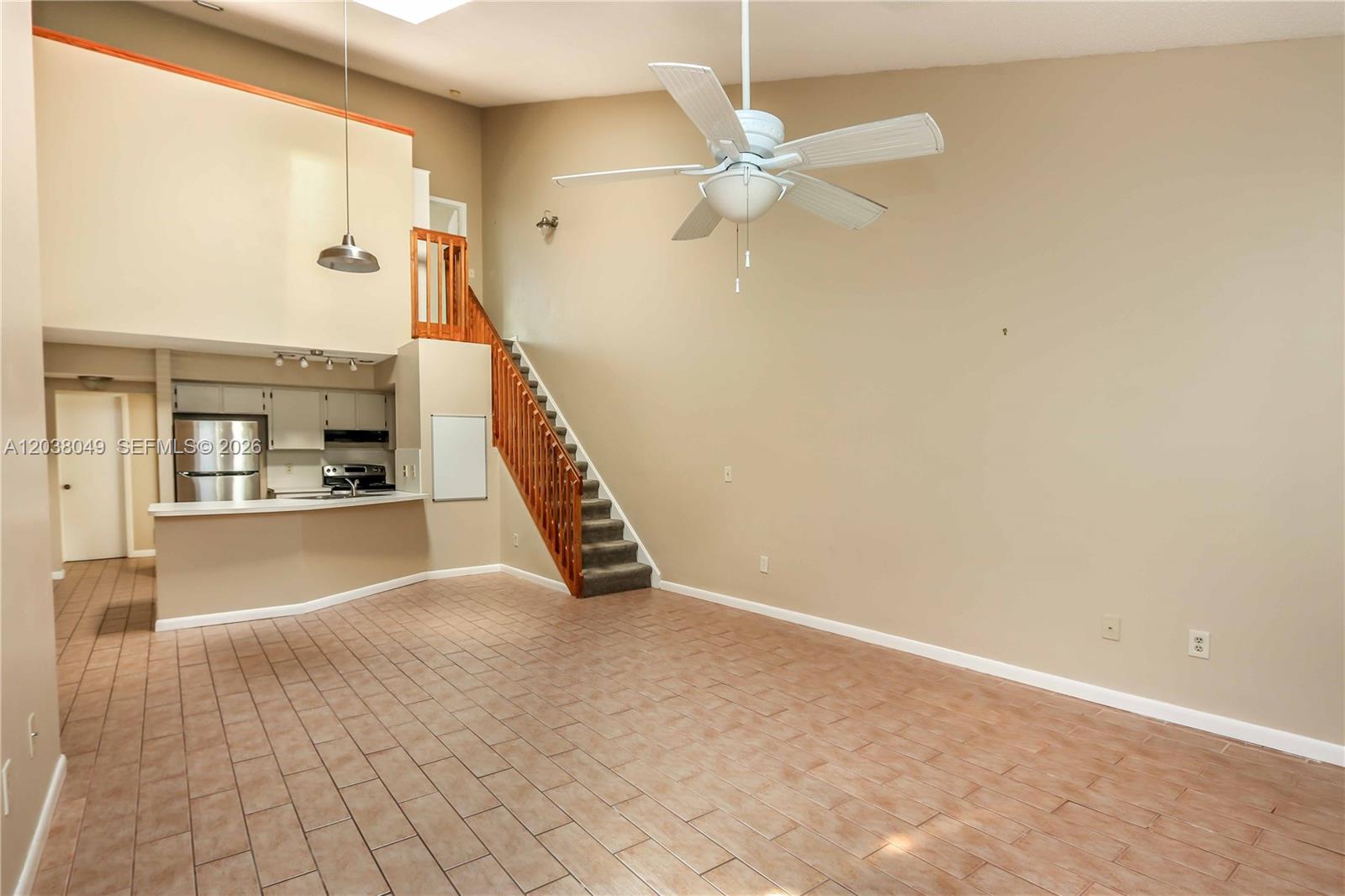 An open living area features tile flooring, a staircase, and a kitchen with a breakfast bar — 444 SE 14th St, Dania Beach FL 33004, DANIA BEACH, FL