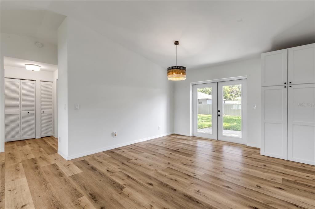 A dining area features light wood-look flooring, white walls, a drum pendant light, and French doors — 2119 LIME TREE DRIVE, EDGEWATER, FL