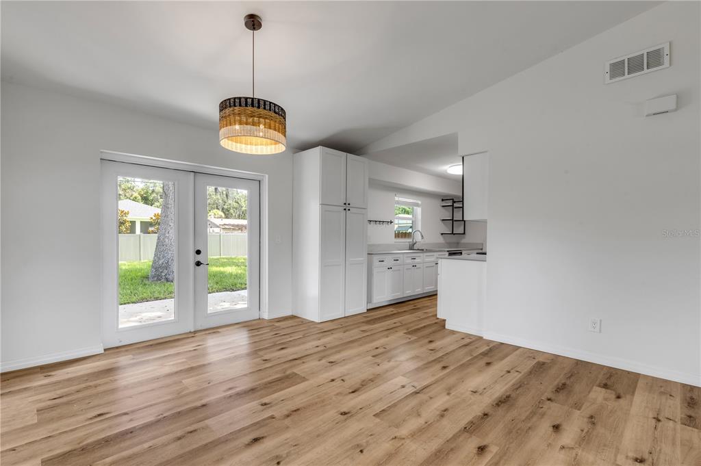 A dining area with wood-look flooring, a woven pendant light, and a view into the kitchen — 2119 LIME TREE DRIVE, EDGEWATER, FL