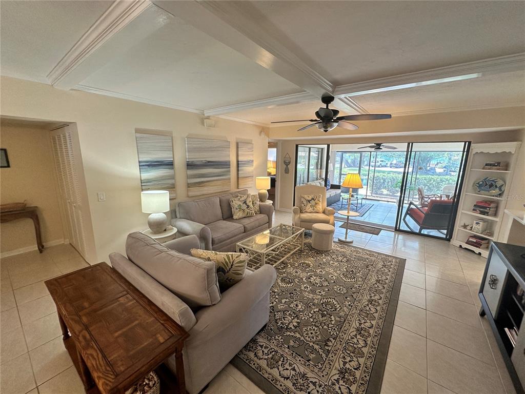 A living room features gray sofas, a patterned area rug, and sliding glass doors — 4572 RED MAPLE ROAD UNIT 901, BRADENTON, FL