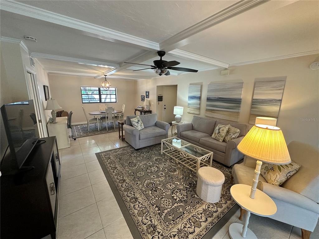 A living room with tile floors, a coffered ceiling, and a dining area in the back — 4572 RED MAPLE ROAD UNIT 901, BRADENTON, FL
