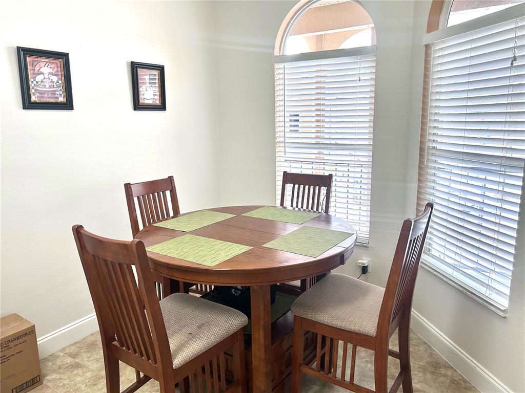 A dining nook features a round wooden table, four chairs, and two arched windows — 8842 CORAL PALMS COURT UNIT B, KISSIMMEE, FL