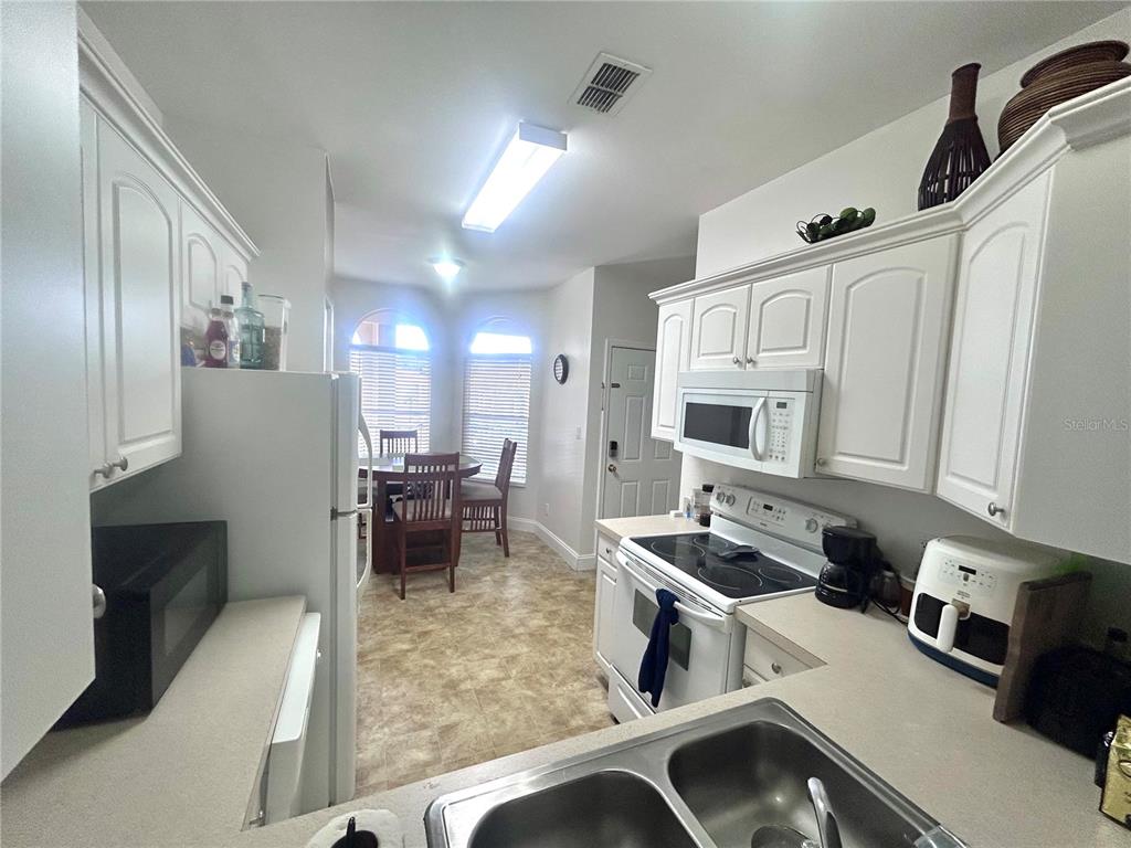 A dining area features a round wooden table, four chairs, and two arched windows — 8842 CORAL PALMS COURT UNIT B, KISSIMMEE, FL