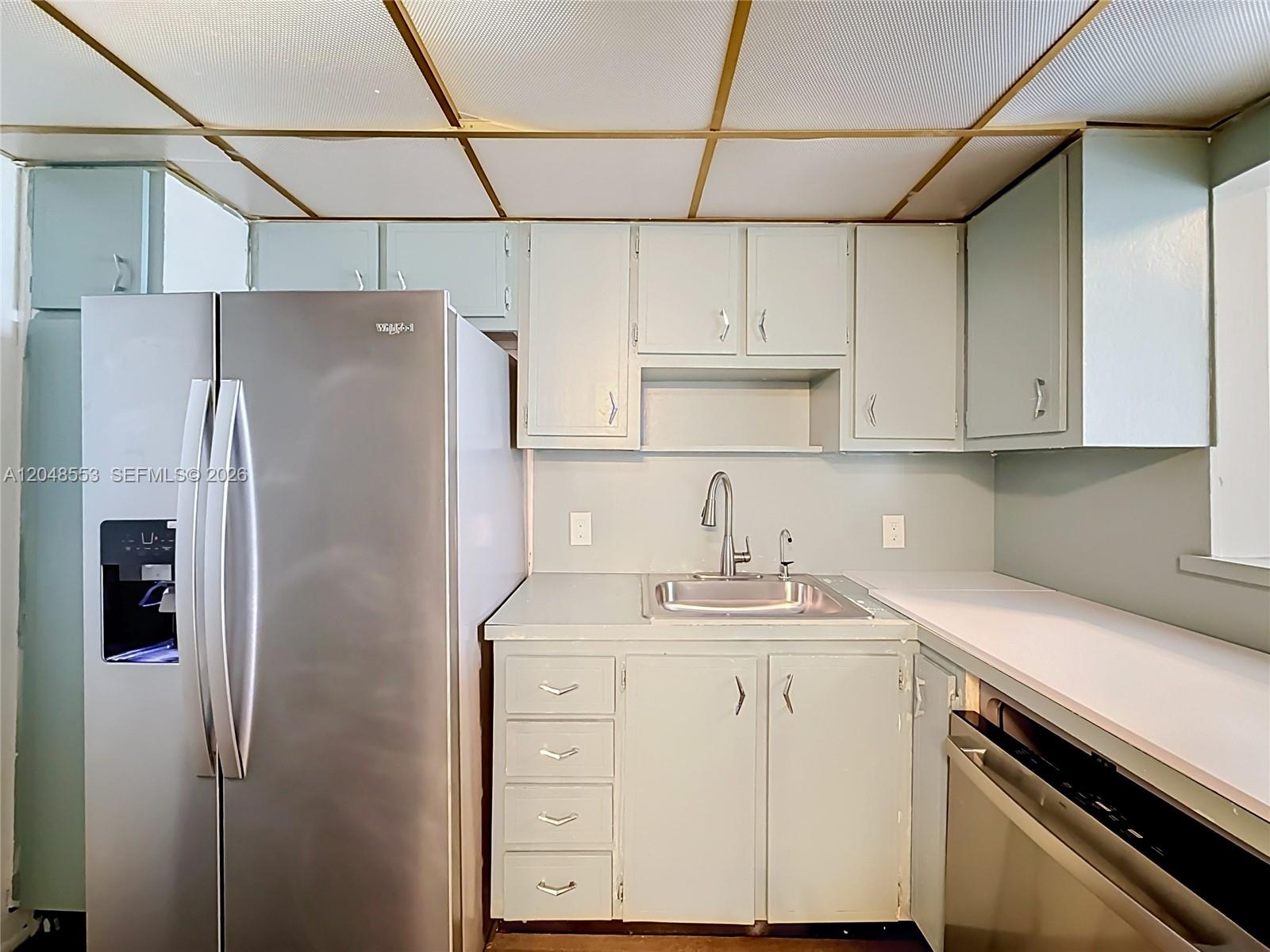 A kitchen features light-colored cabinets, a stainless steel refrigerator, a sink, and a drop ceiling — 1228 West Ave # 208, Miami Beach FL 33139, MIAMI BEACH, FL