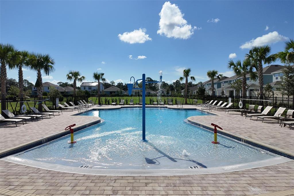 A swimming pool with a central water feature is surrounded by lounge chairs and palm trees — 5893 ALI GRACE DRIVE, ST CLOUD, FL