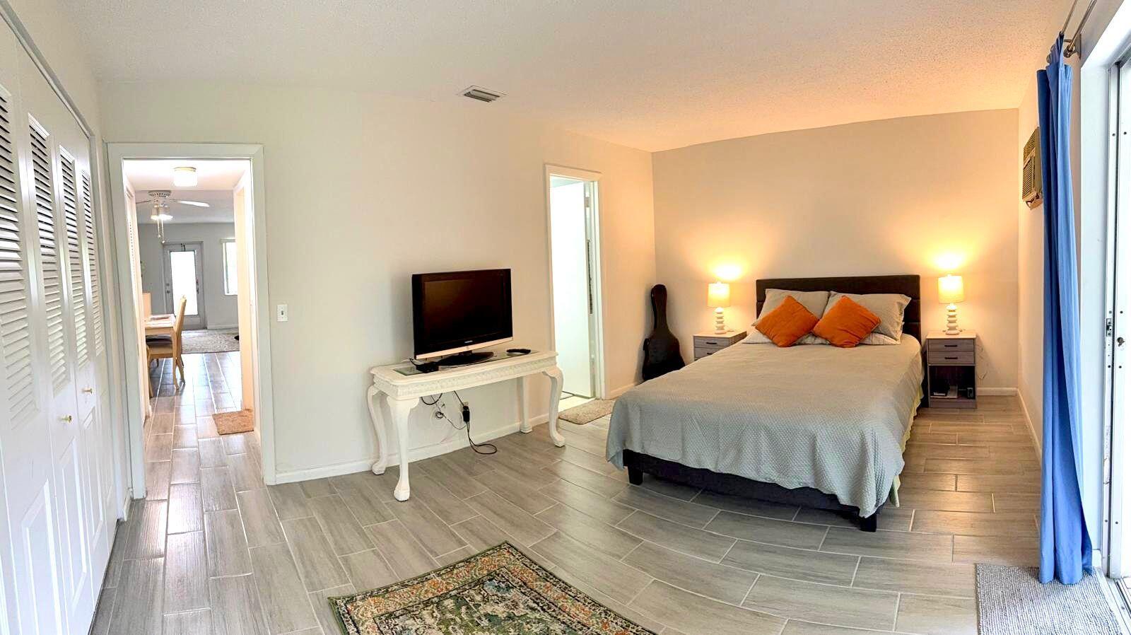 A bedroom with a bed, television on a console table, and light-colored tile flooring — 63 Windsor C, West Palm Beach FL 33417, WEST PALM BEACH, FL