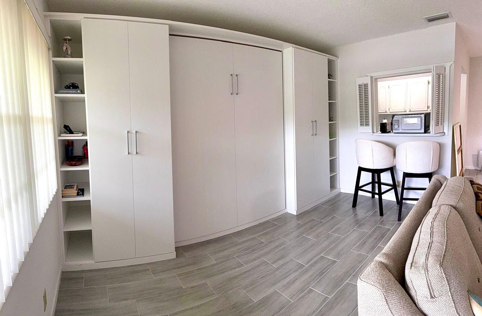 A room features a white Murphy bed unit with side shelving, tile flooring, and bar seating — 63 Windsor C, West Palm Beach FL 33417, WEST PALM BEACH, FL