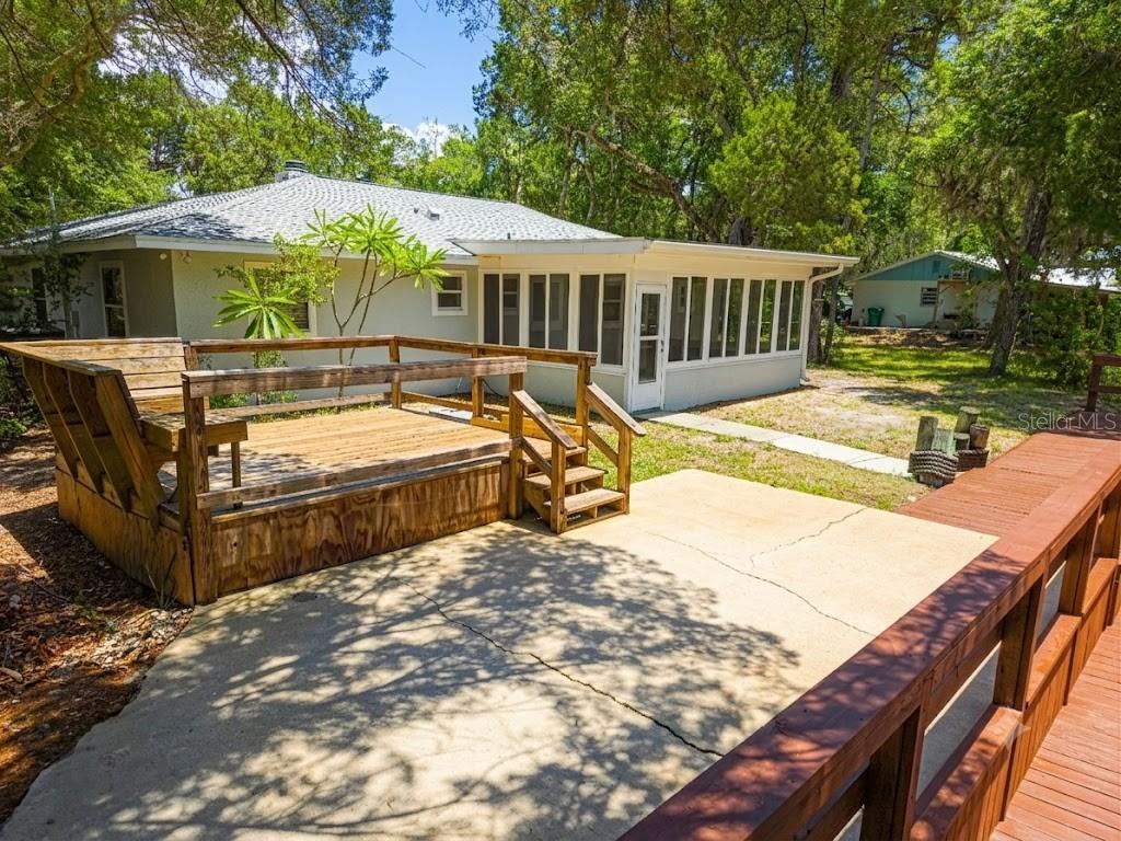 A backyard features a wooden deck with built-in seating, a concrete patio, and a sunroom — 6806 S HOLLY OAK POINT, HOMOSASSA, FL