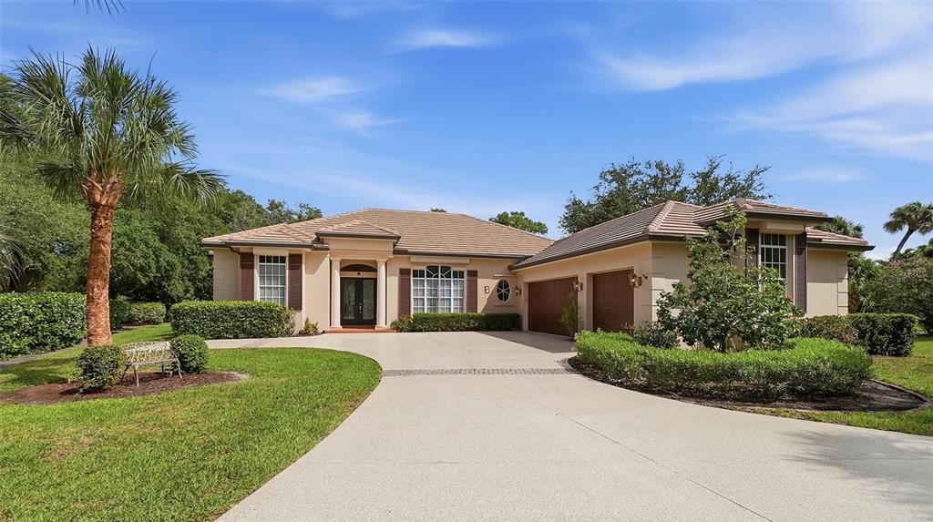 A single-story house with a beige stucco exterior, a tile roof, and a paved driveway — 27 DOMINICA DRIVE, ENGLEWOOD, FL