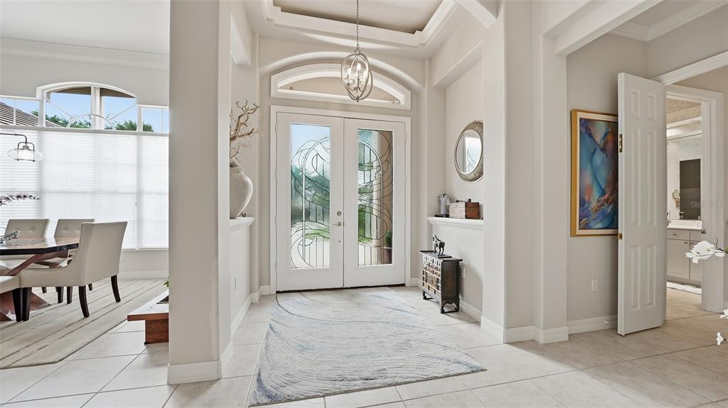 A bright entryway features double glass-paneled doors, tile flooring, and a decorative ceiling light fixture — 27 DOMINICA DRIVE, ENGLEWOOD, FL