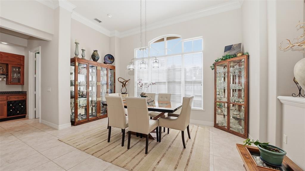A dining room features a glass table, upholstered chairs, two display cabinets, and large windows — 27 DOMINICA DRIVE, ENGLEWOOD, FL
