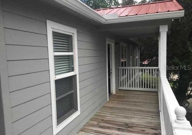 A gray-sided house features a wooden deck with a white railing and a metal roof — 2905 SW ARCHER ROAD UNIT T-5027, GAINESVILLE, FL