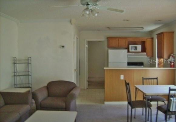 A living room with a brown armchair leads into a kitchen with wooden cabinets — 2905 SW ARCHER ROAD UNIT T-5027, GAINESVILLE, FL