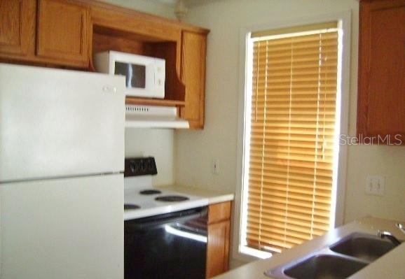 A kitchen features light wood cabinets, a white refrigerator, a stove, and a window — 2905 SW ARCHER ROAD UNIT T-5027, GAINESVILLE, FL