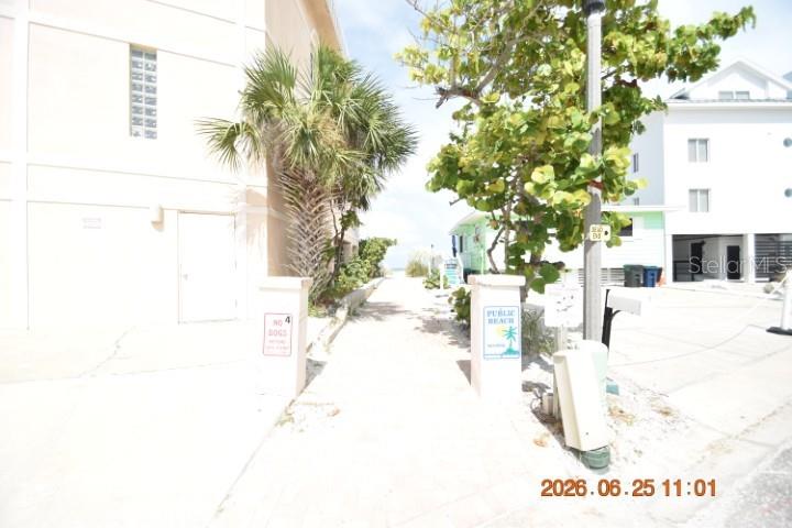 A paved walkway leads between two buildings toward a public beach access point — 146 CORAL AVENUE UNIT C, ST PETERSBURG, FL