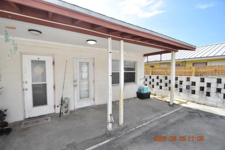 A concrete patio area with two white doors, support columns, and a block wall — 146 CORAL AVENUE UNIT C, ST PETERSBURG, FL