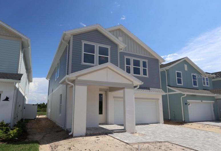 A two-story house with blue siding, a white covered entryway, and a paved driveway — 3395 YELLOW CASSIA DRIVE, WESLEY CHAPEL, FL