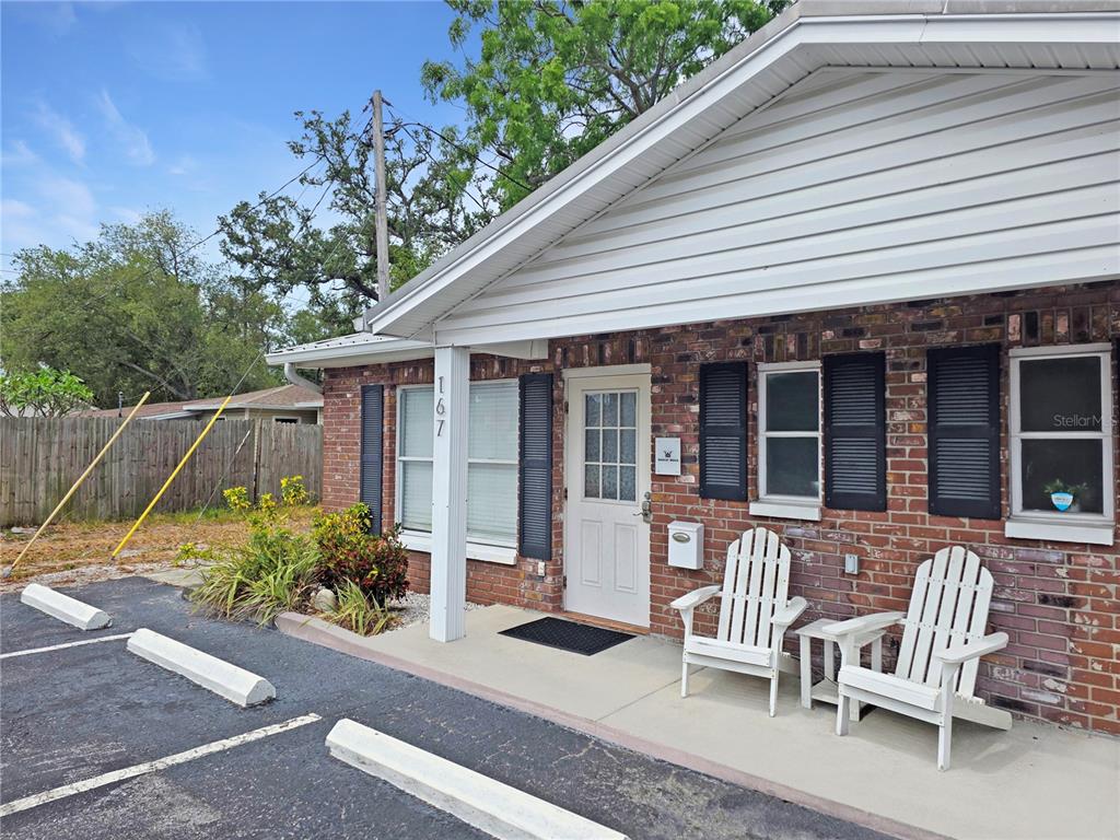 A brick building exterior features a white door, two white chairs, and a parking space — 167 6TH STREET SW, LARGO, FL