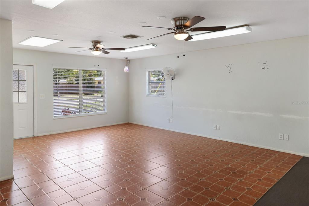 A spacious room features terracotta-style tile flooring, two ceiling fans, and multiple light fixtures — 167 6TH STREET SW, LARGO, FL