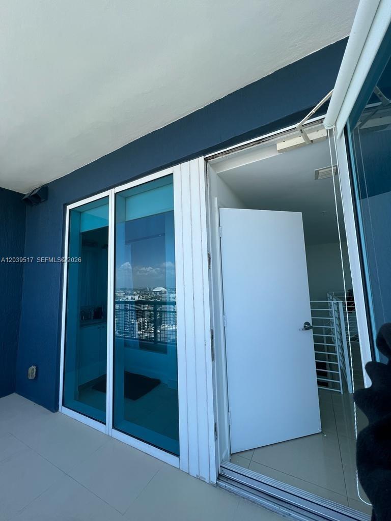 A view from a balcony looking through a glass door into an interior room — 60 SW 13th St # 2819, Miami FL 33130, MIAMI, FL