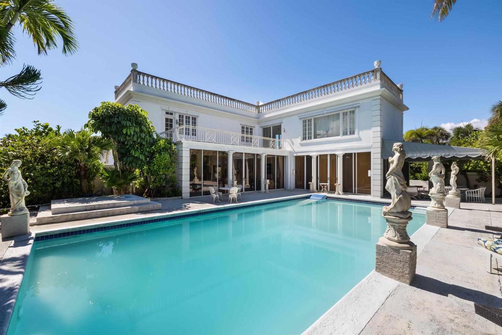 A white two-story house with a swimming pool and classical statues on the patio — 1048 S Ocean Boulevard, Palm Beach FL 33480, PALM BEACH, FL