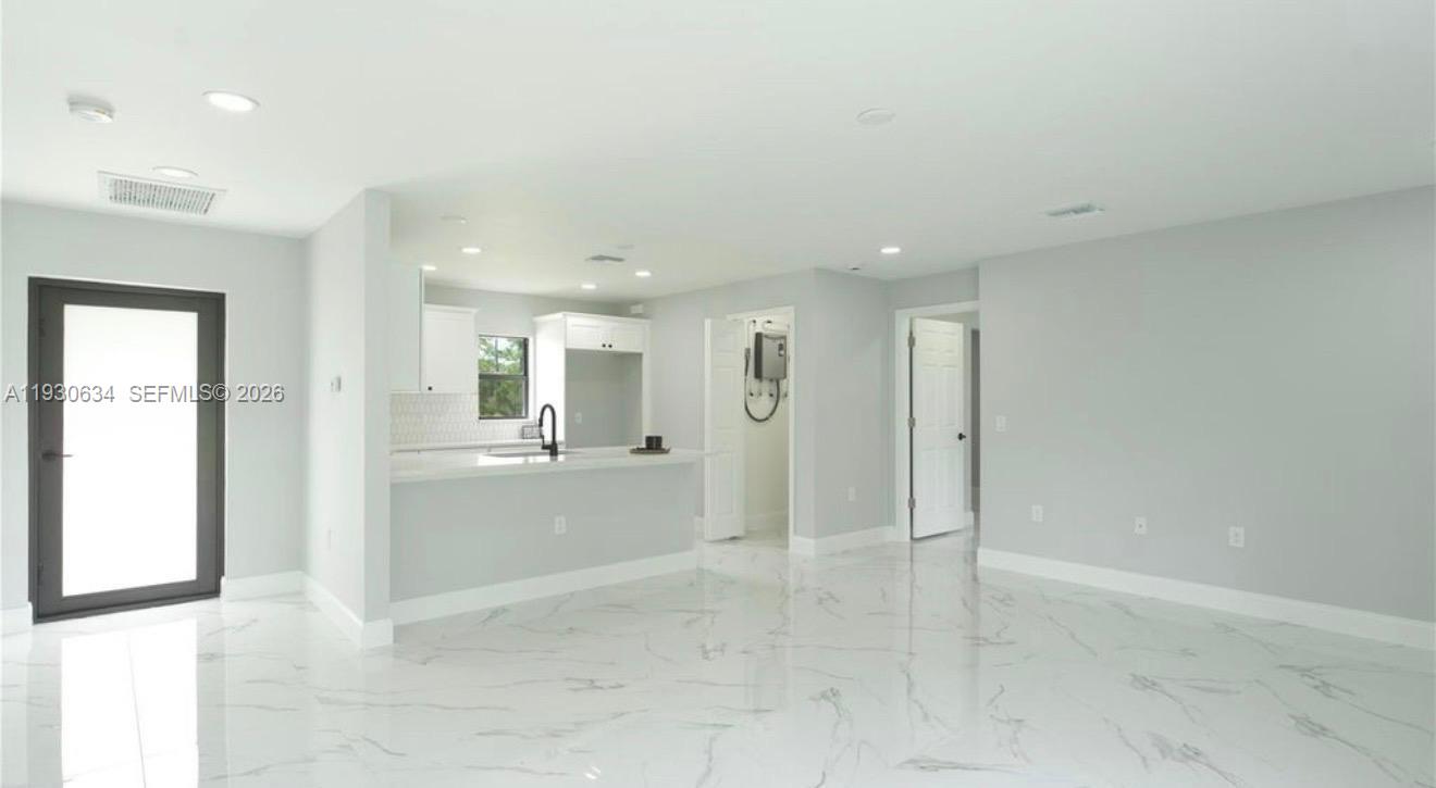 A bright, open-concept living area features white marble-look tile flooring and a modern kitchen — 761 Kirkman Ave # 0, Lehigh Acres FL 33074, LEHIGH ACRES, FL