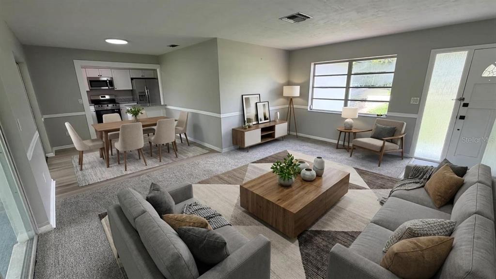 An open-concept living and dining area features gray walls, neutral furniture, and a wooden coffee table — 658 ELGROVE DRIVE, DELTONA, FL