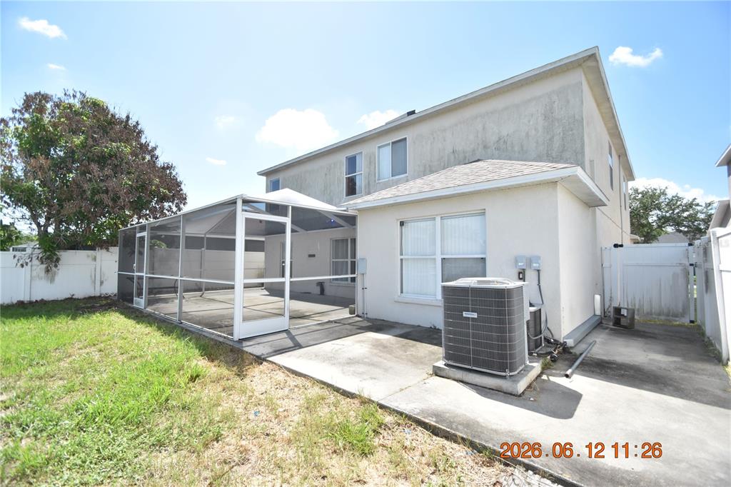 The rear exterior of a two-story house features a screened-in patio and an air conditioner — 10924 SUBTLE TRAIL DRIVE, RIVERVIEW, FL