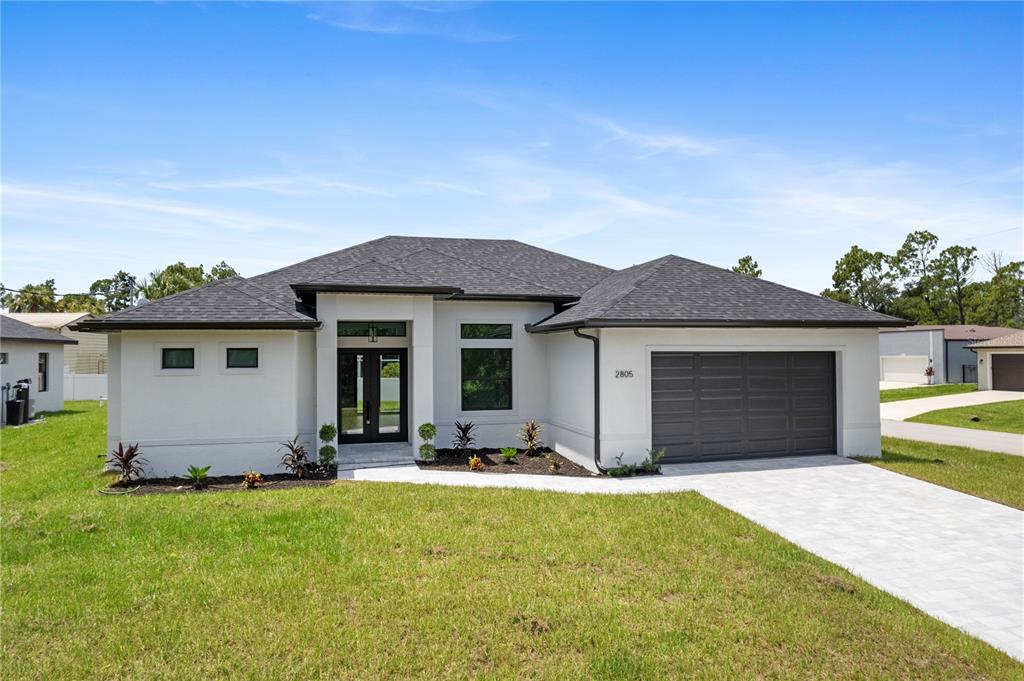 A single-story white house with a dark roof, double front doors, and a two-car garage — 2805 ANNISTON ROAD, NORTH PORT, FL