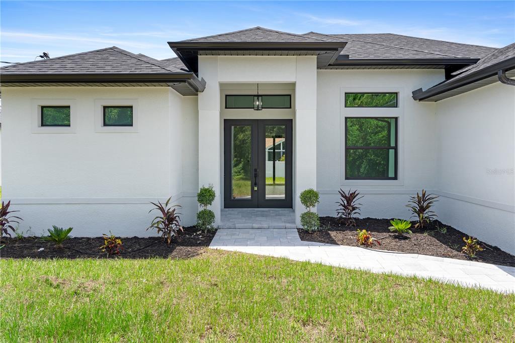 A modern white house exterior features a dark double front door and a paved walkway — 2805 ANNISTON ROAD, NORTH PORT, FL