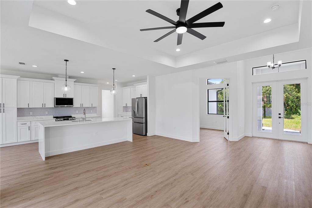 A modern open-concept kitchen and living area with white cabinetry, a large island, and flooring — 2805 ANNISTON ROAD, NORTH PORT, FL