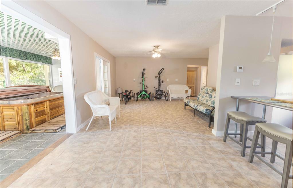 A spacious room with tile flooring features a hot tub, seating, and three bicycles — 5175 AZALEA CIRCLE, DADE CITY, FL