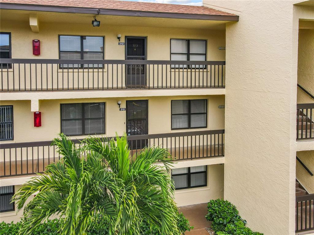 An exterior view of a multi-story apartment building with balconies and numbered unit doors — 425 30TH AVENUE W UNIT C212, BRADENTON, FL
