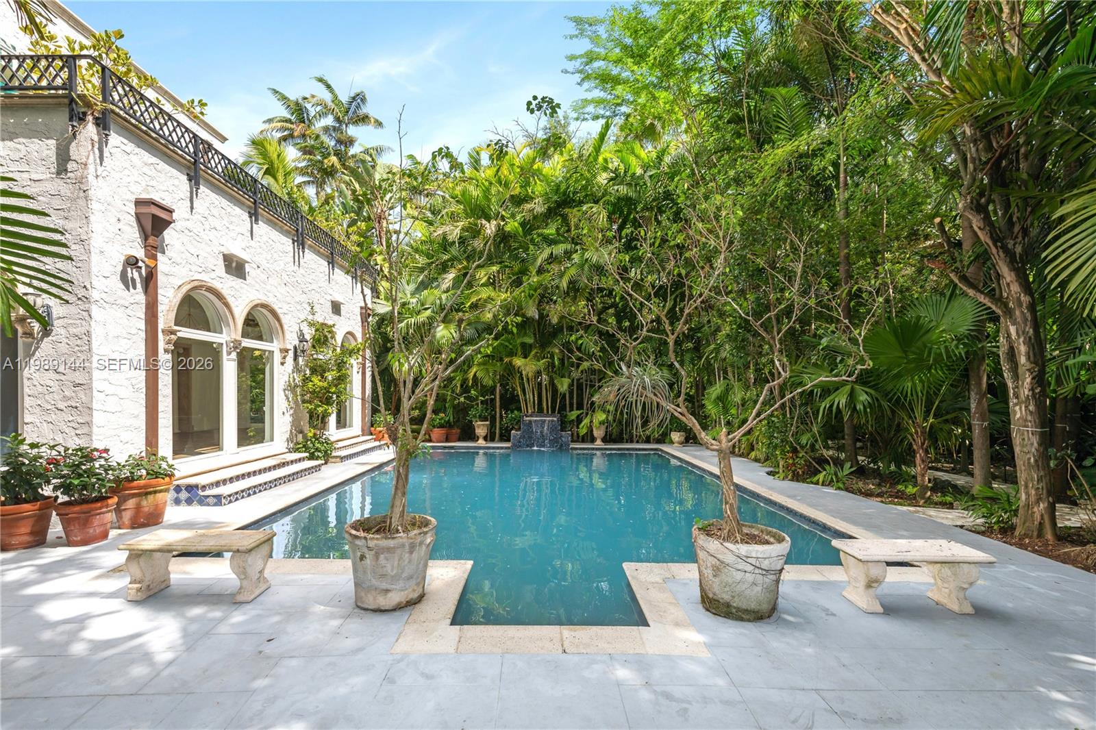 A rectangular swimming pool sits in a courtyard next to a white stucco building — 3685 Royal Palm Ave, Miami FL 33133, MIAMI, FL