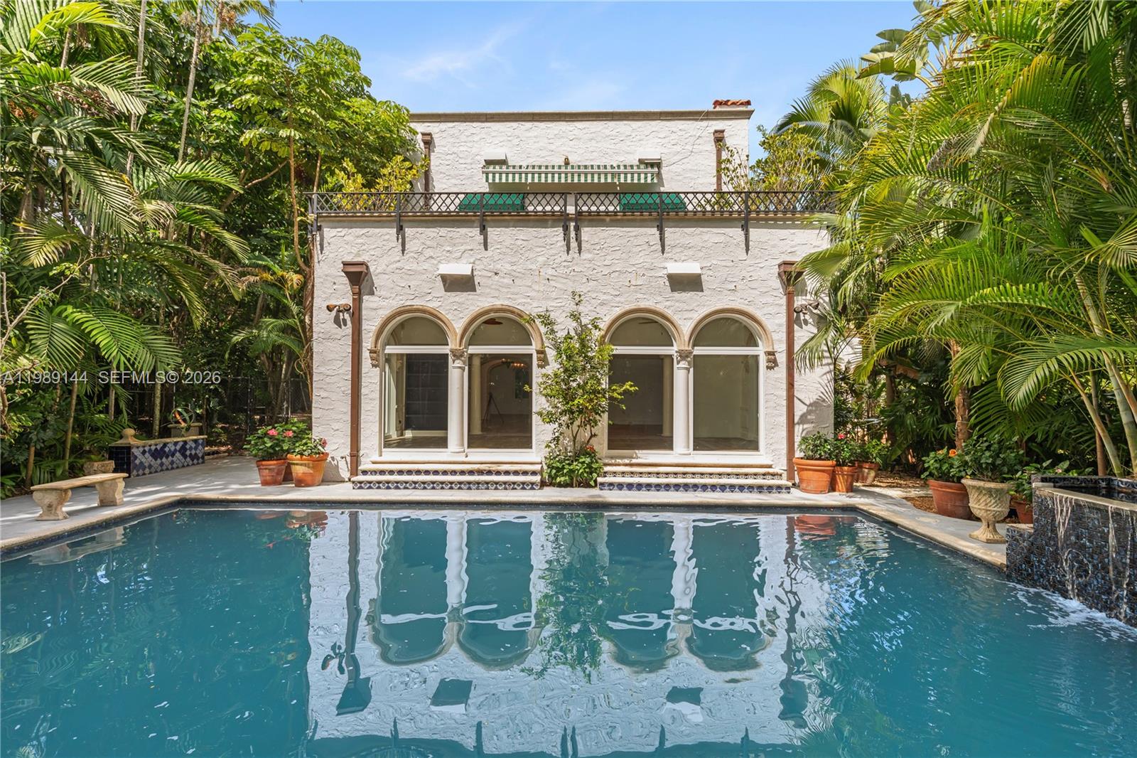 A swimming pool sits in front of a white two-story house with arched glass doors — 3685 Royal Palm Ave, Miami FL 33133, MIAMI, FL