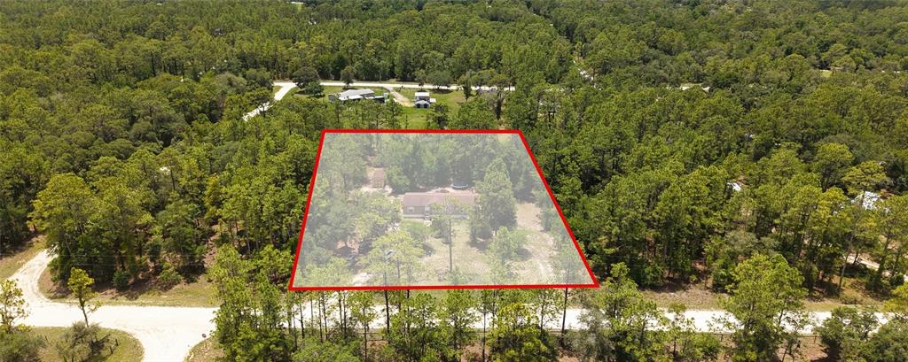 An aerial view shows a house situated on a wooded lot outlined in red — 14050 SE 20 STREET, MORRISTON, FL