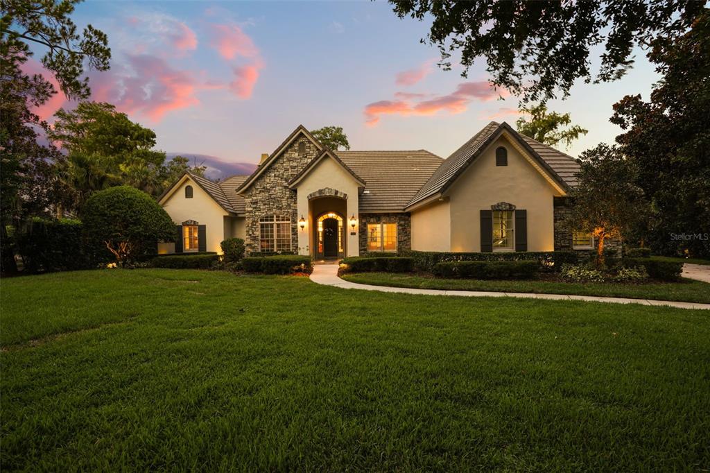A single-story house with a stone facade and arched entryway sits behind a large lawn — 5115 CRANES POINT COURT, ORLANDO, FL