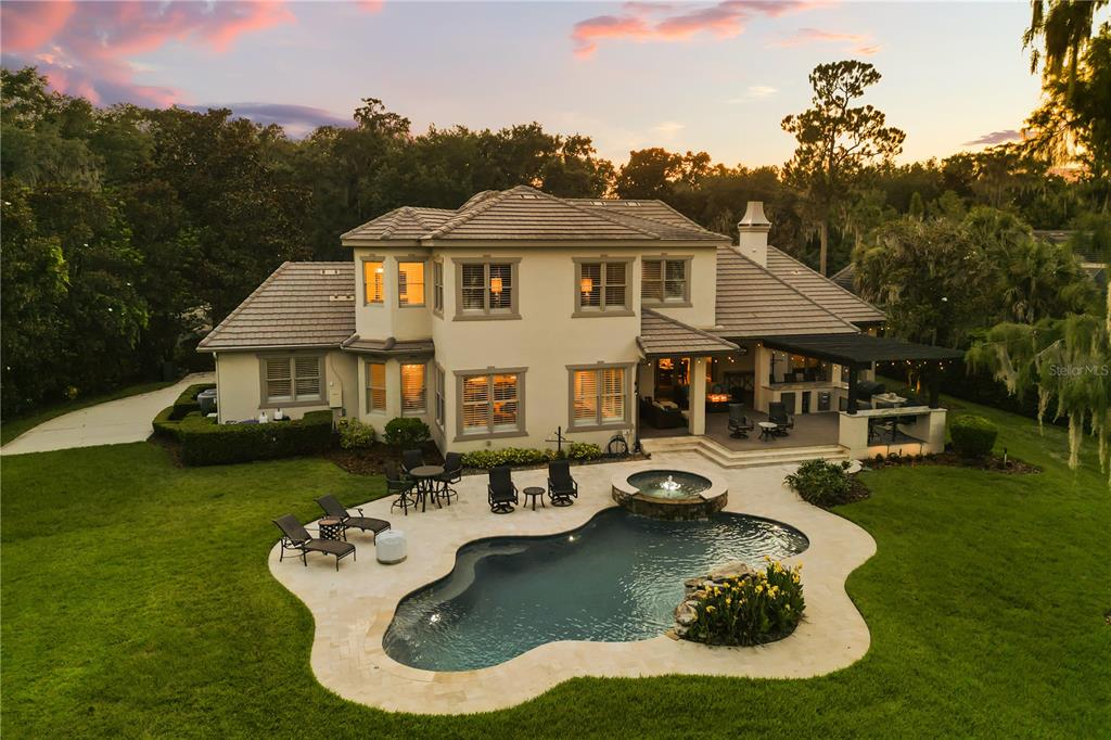 A wooden dock with a covered boat slip extends into a lake at sunset — 5115 CRANES POINT COURT, ORLANDO, FL