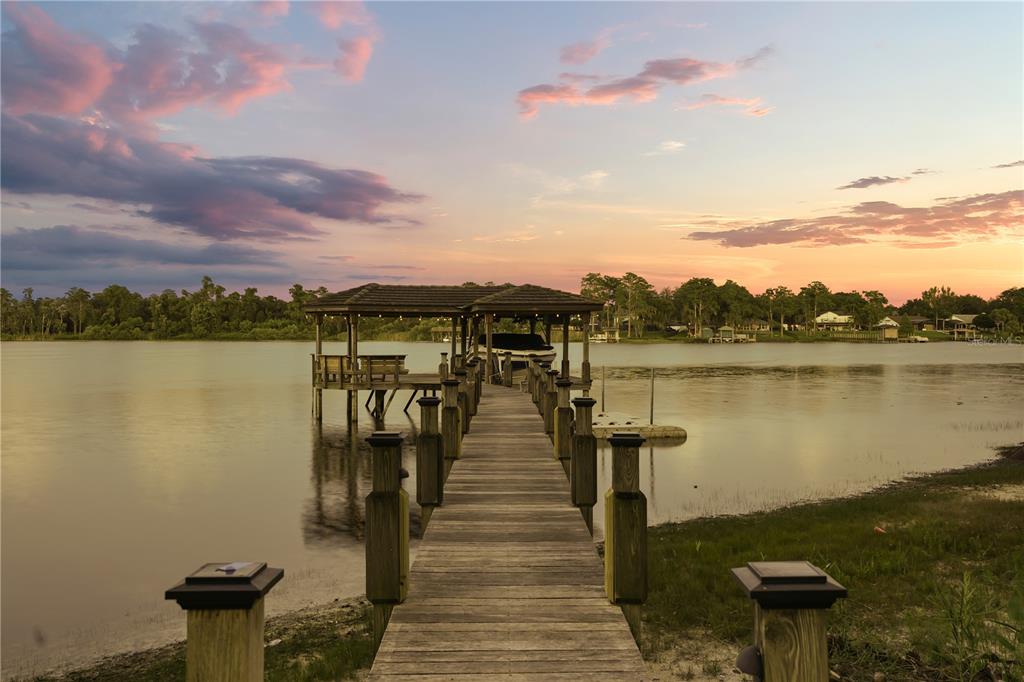 A two-story house with a backyard pool, stone patio, and outdoor kitchen at sunset — 5115 CRANES POINT COURT, ORLANDO, FL