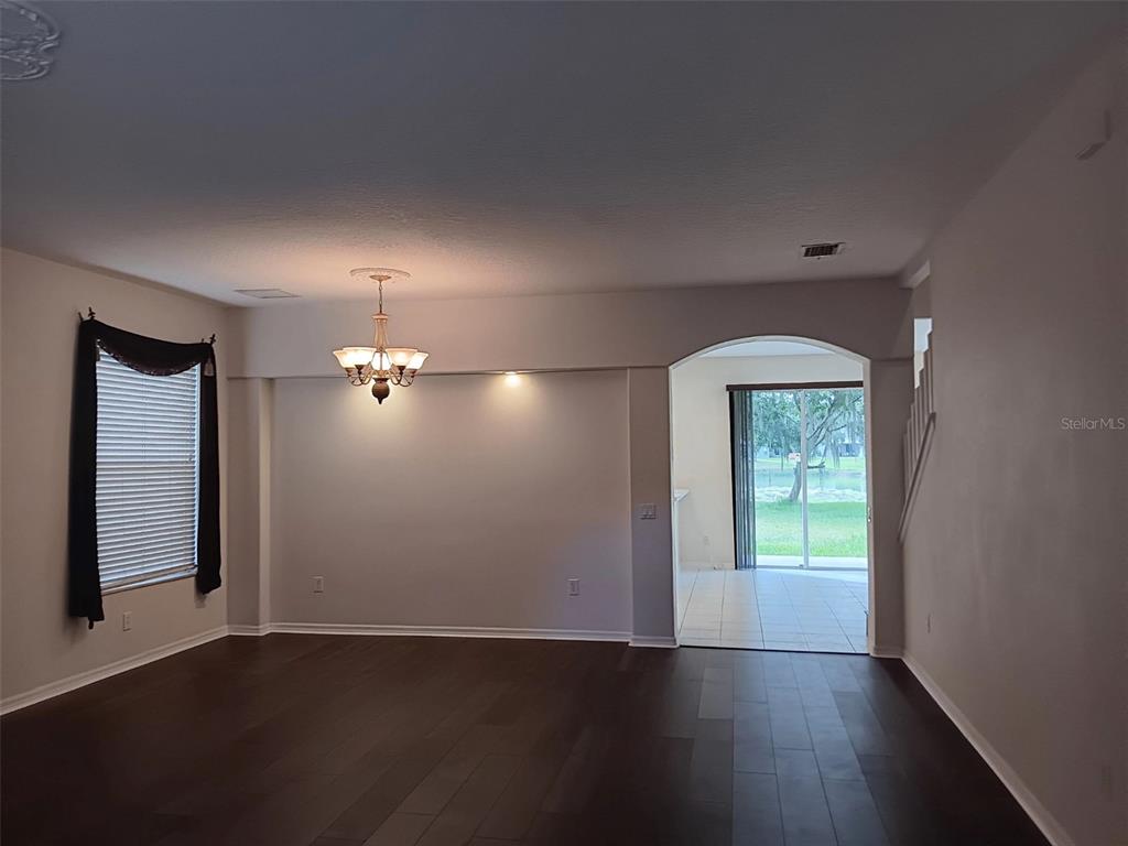 A dining area with dark wood floors, a chandelier, and an arched doorway to a patio — 10415 LUCAYA DRIVE, TAMPA, FL