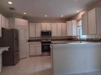 A kitchen features white cabinets, stainless steel appliances, a tile floor, and a breakfast bar — 10415 LUCAYA DRIVE, TAMPA, FL
